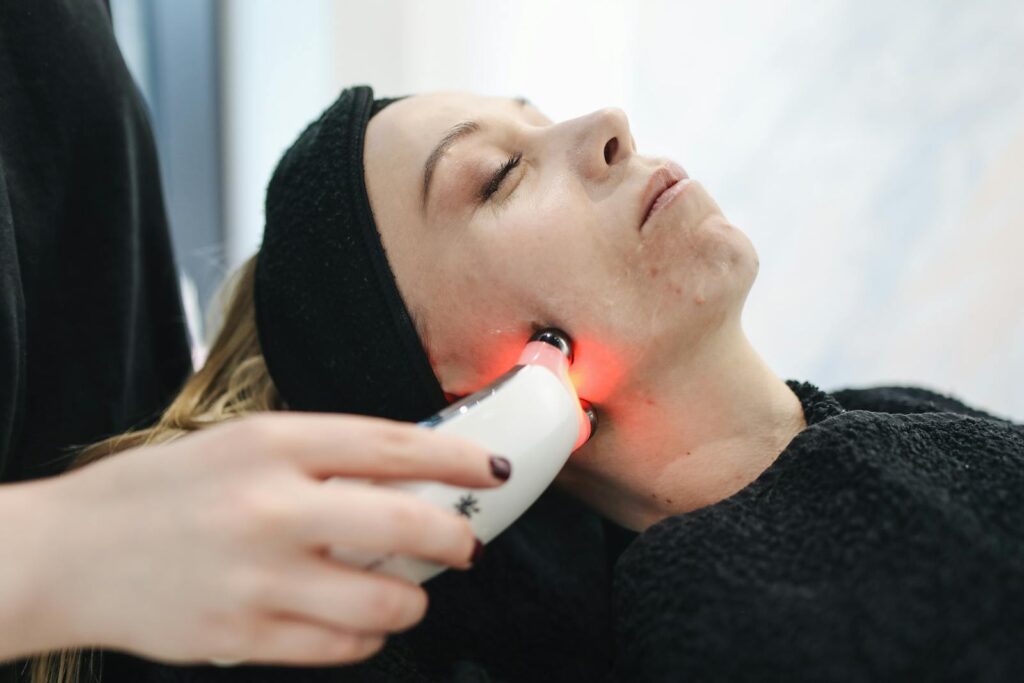 An adult woman receives a laser facial treatment in a modern skincare clinic.