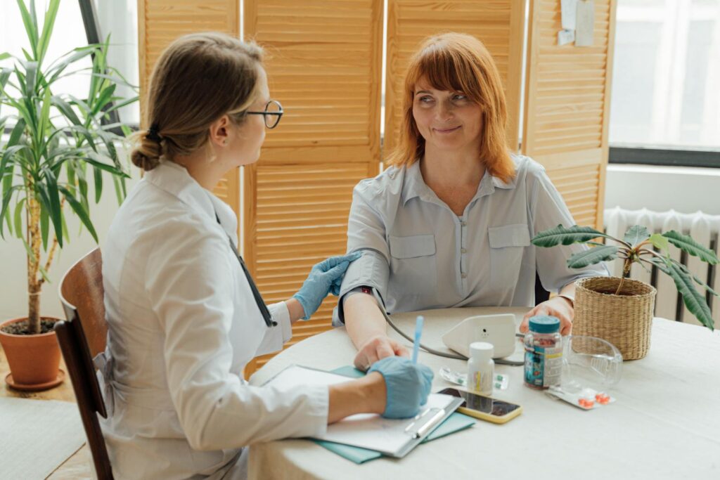 Doctor measuring patient's blood pressure with digital monitor in a clinical setting.