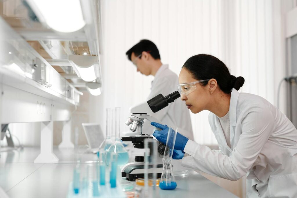 Two scientists in a lab examining samples with a microscope. Focus on scientific research and discovery.